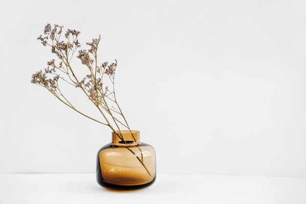 Ramo di fiori in un vaso di vetro sul tavolo bianco. Arredamento per interni. Decorazione alla moda per la casa.