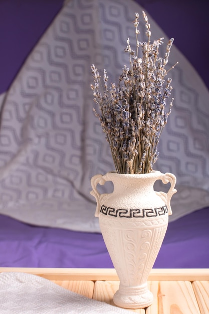 Ramoscelli di lavanda in un vaso su uno sfondo lilla con un caldo plaid bianco Bouquet di fiori Provenza