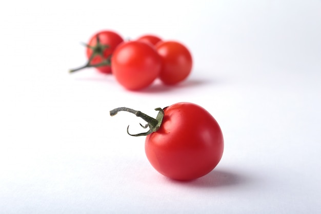 Ramoscello di pomodori freschi con foglie verdi isolato su bianco.