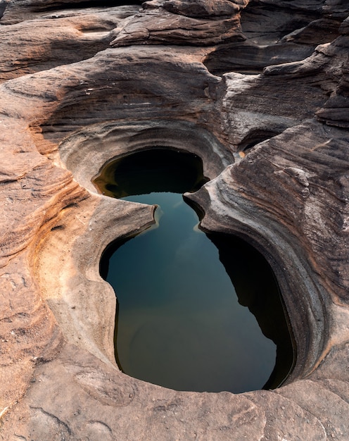 Rapide naturali di roccia erosa con foro di roccia rotondo e acqua