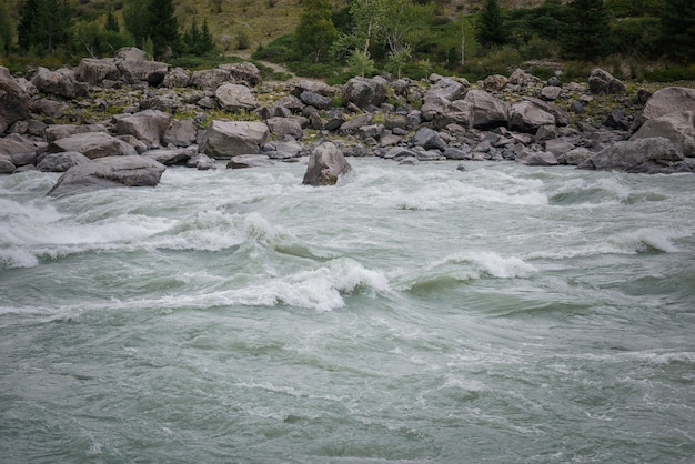 Rapido flusso d'acqua nel fiume di montagna sullo sfondo di sponde rocciose, zona per il rafting, alto livello di difficoltà.