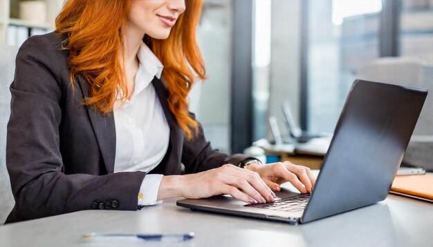 Rapporto ravvicinato di una donna d'affari che lavora e digita sulla tastiera di un computer portatile sul tavolo dell'ufficio online con...