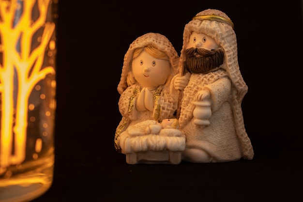 Rappresentazione di un presepe di Natale con le piccole figure di Gesù bambino, Maria e Giuseppe su sfondo nero.