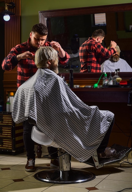 Rasatura alla moda e alla moda Parrucchiere in barbiere uomo in parrucchiere con barba e baffi taglio di capelli hipster Parrucchiere professionista in interni da barbiere Ritratto di barba uomo alla moda