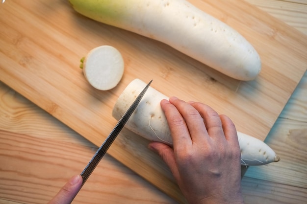 Ravanello daikon bianco fresco con fetta sullo sfondo di legno Ravanelli coreani tagliati a mano