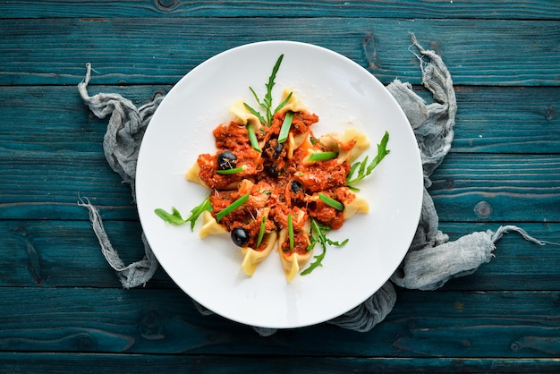 Ravioli con carne e salsa di pomodoro e olive In un piatto su uno sfondo di legno Vista dall'alto Spazio libero per la copia