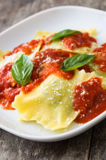 Ravioli con salsa al pomodoro e basilico su fondo di legno.