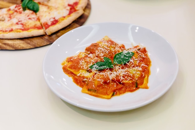 Ravioli con salsa di pomodoro e basilico conditi con parmigiano a fette