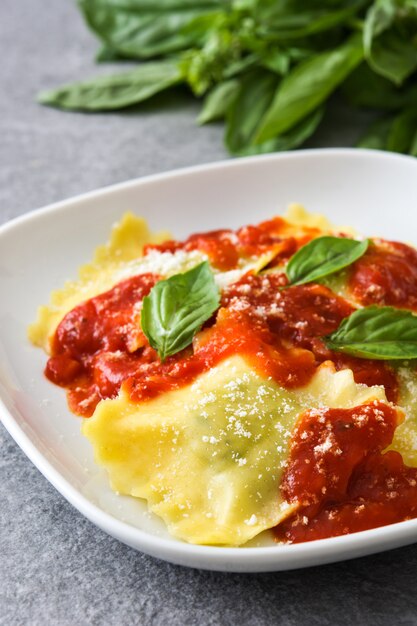 Ravioli con salsa di pomodoro e basilico su pietra grigia