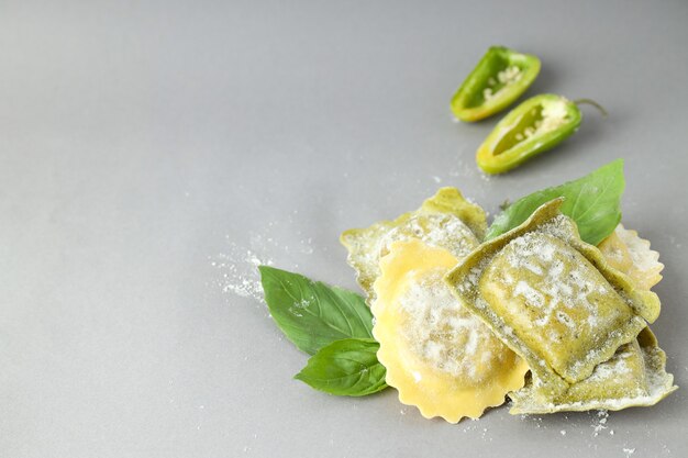 Ravioli crudi con spezie su fondo grigio chiaro