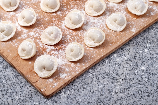 Ravioli crudi (o gnocchi) su tavola di legno su tavola di pietra.