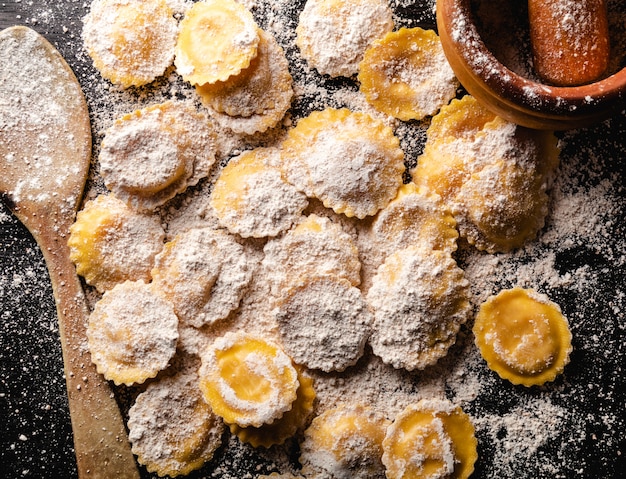 Ravioli crudi saporiti con farina e basilico sulla tavola di legno