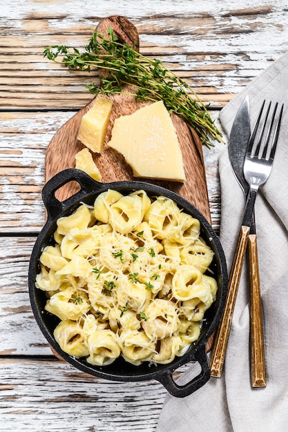 Ravioli di parmigiano in padella. Gnocchi italiani. Fondo in legno bianco. Vista dall'alto.