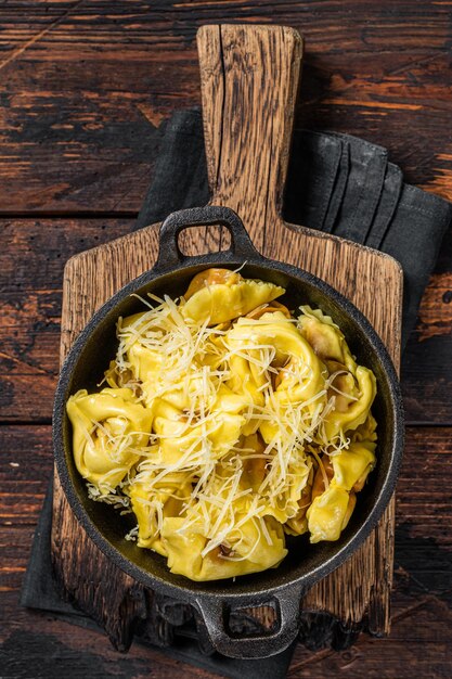 Ravioli di pasta con mozzarella, parmigiano e pomodoro. Fondo in legno. Vista dall'alto.