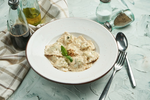 Ravioli di pasta italiana classici con aggiunta di spinaci con vari ripieni (salmone, formaggio, verdure o carne) in salsa cremosa in una ciotola beige