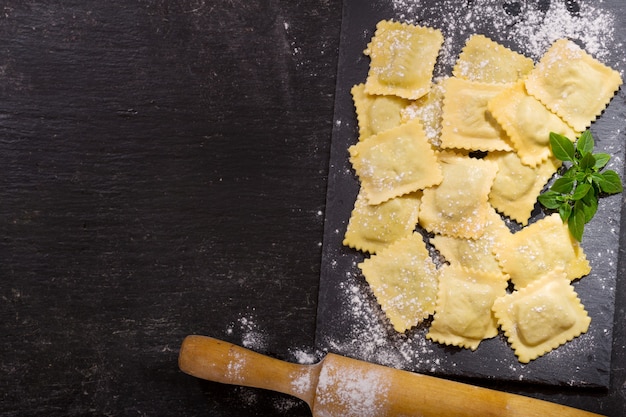 Ravioli freschi con basilico a bordo scuro, vista dall'alto