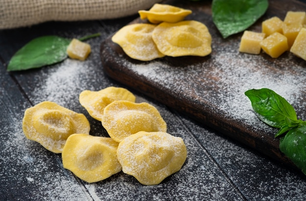 Ravioli freschi con formaggio e basilico cosparsi di farina su tavola di legno