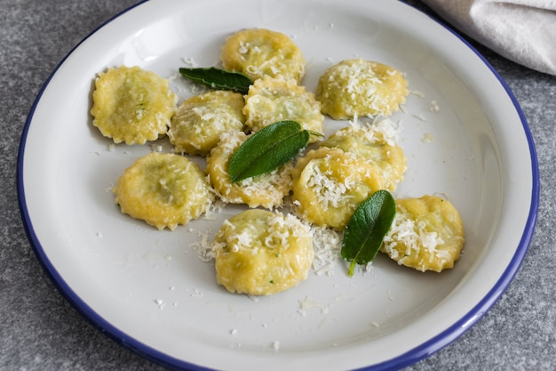 Ravioli italiani cucinati freschi con la ricotta e gli spinaci sulla tavola grigia