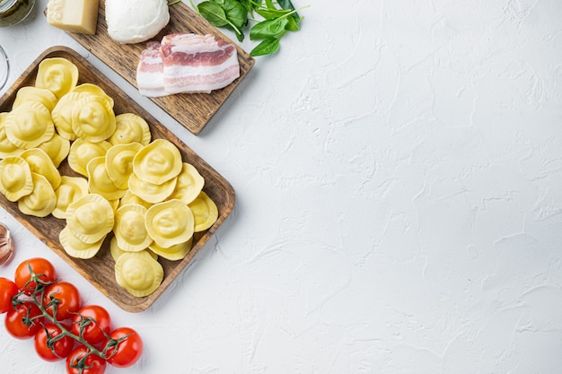 Ravioli italiani fatti in casa con ingredienti, prosciutto, basilico, pesto, set di mozzarella, sul vassoio in legno, vista dall'alto