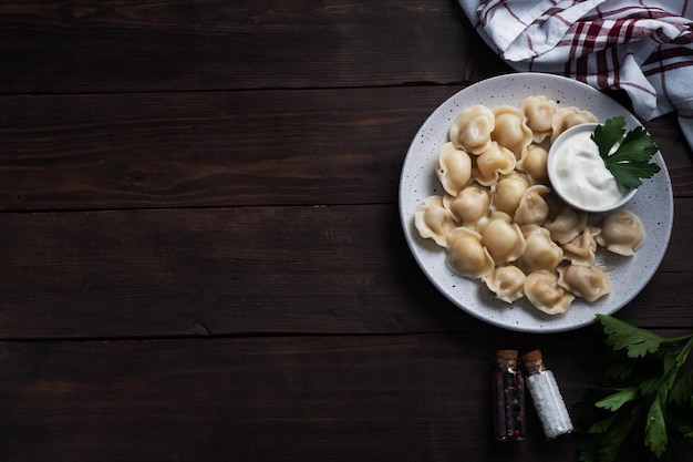 Ravioli tradizionali pelmeni gnocchi ripieni di carne su piastra cucina russa Rustico in legno sfondo spazio copia