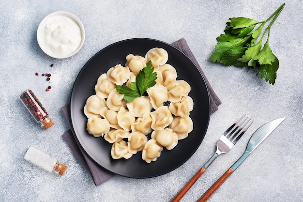 Ravioli tradizionali pelmeni gnocchi ripieni di carne su piastra cucina russa Spazio per la copia di sfondo in cemento chiaro