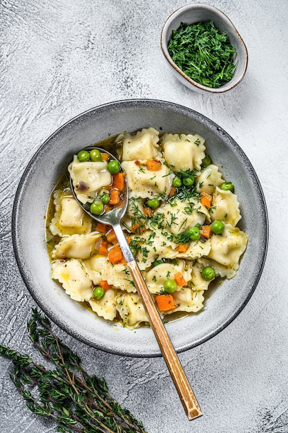 Ravioli Zuppa di gnocchi di pasta in una ciotola con verdure. Sfondo bianco. Vista dall'alto.