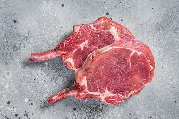 raw tomahawk beef veal steak on butcher table gray background top view