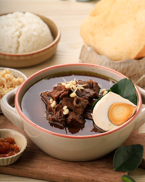 Rawon è una zuppa di manzo nera originaria di East Java, Indonesia. Servito con riso e uova salate. Deliziosa spezia ricca ed erbe tradizionali indonesiane. Servito in una ciotola di ceramica.
