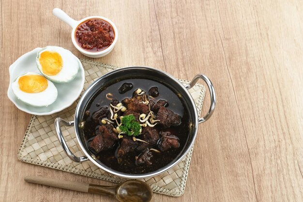 Rawon Indonesian Tradizionale zuppa nera di manzo Servita su una ciotola con pasta di peperoncino e germogli di fagioli mung