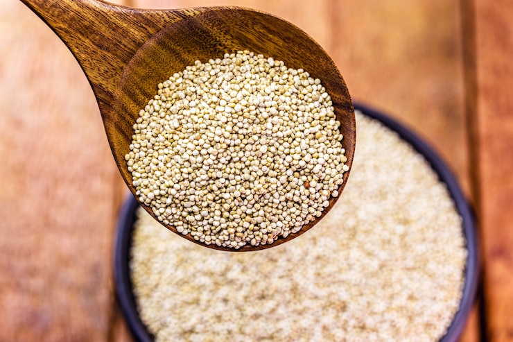 Photo real white quinoa in a natural wooden spoon with clay bowl. top view