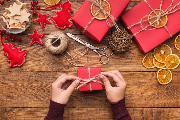 Realizzazione di scatole regalo creative artigianali, donna che decora i regali di Natale con decorazioni naturali, vista dall'alto