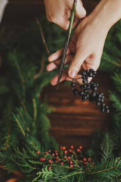 Realizzazione di una ghirlanda natalizia rustica, officina invernale stagionale Fiorista che tiene forbici e bacche