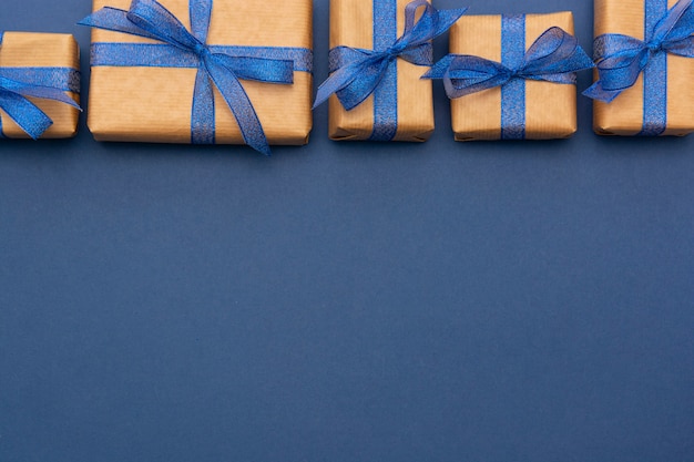 Realizzi i contenitori di regalo avvolti carta in una fila sul blu
