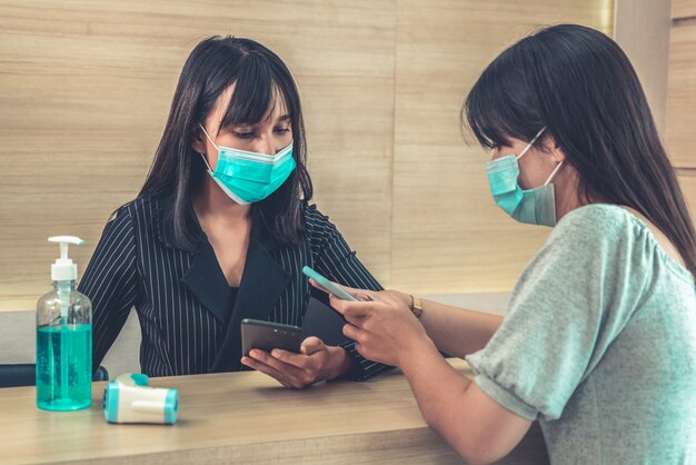 Receptionist e ospite che indossa la maschera per il viso alla reception.