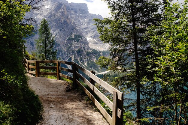 Recinzione in legno lungo un sentiero escursionistico in montagna con vista sul lago e sulle montagne