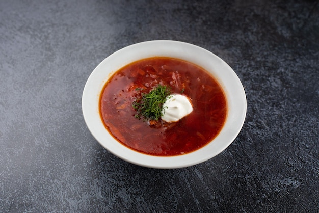 Red delizioso delizioso borscht in un piatto bianco su sfondo grigio