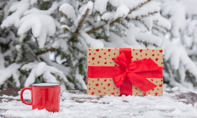 Red tazza di caffè e confezione regalo sulla tavola di legno nella neve