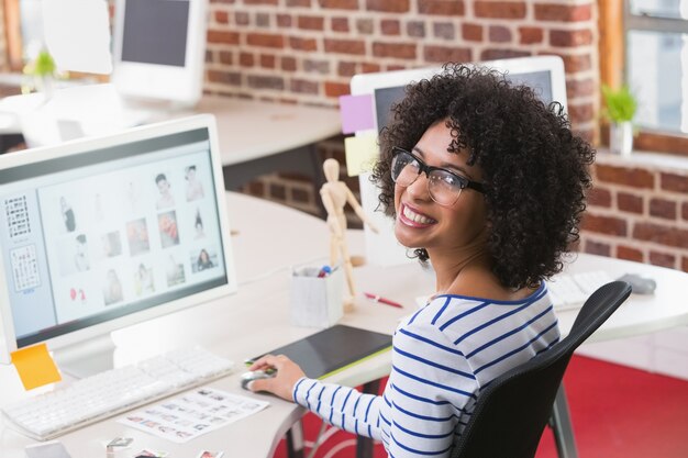 Redattore di foto femminile sorridente alla scrivania