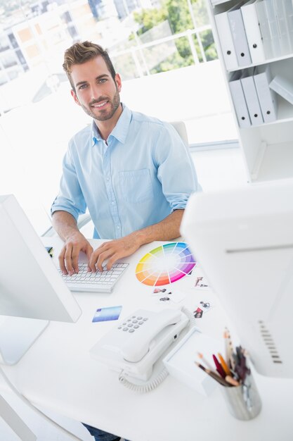 Redattore di foto maschio sorridente che per mezzo del computer