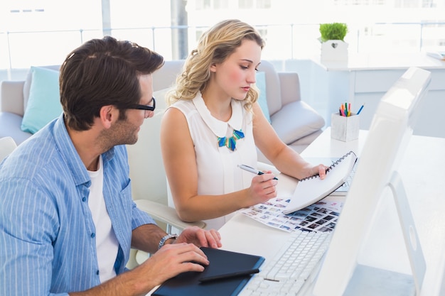 Redattori di foto che lavorano con tavoletta grafica e blocco note