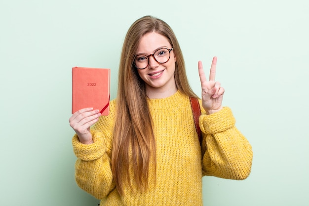 Redhair donna sorridente e dall'aspetto amichevole che mostra il concetto di pianificatore numero due