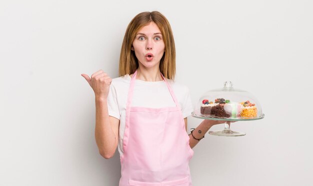 Redhead bella ragazza che sembra stupita nell'incredulità del concetto di torte fatte in casa