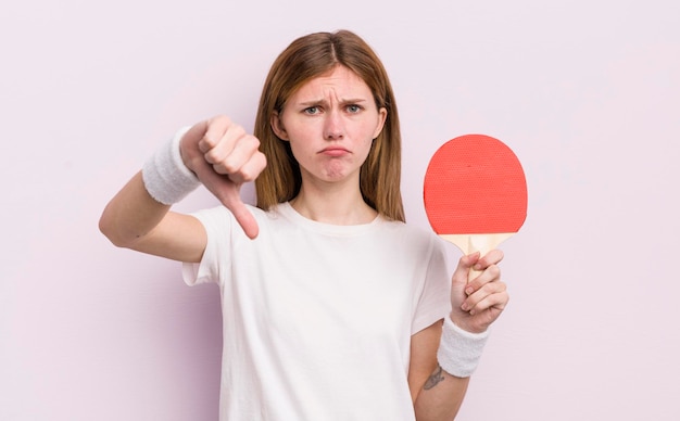 Redhead bella ragazza che si sente crossshowing pollice verso il concetto di ping pong