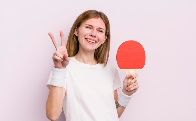 Redhead bella ragazza sorridente e guardando felice gesturing vittoria o pace ping pong concetto