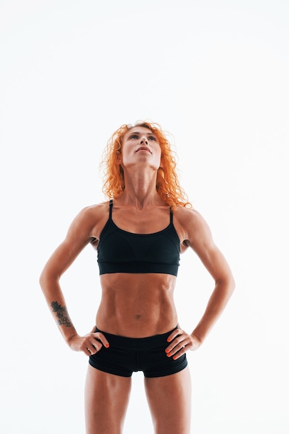 Redhead femminile bodybuilder è in studio su uno spazio bianco.