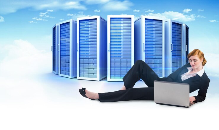 Foto redhead imprenditrice utilizzando il suo computer portatile contro l'immagine composita delle torri del server
