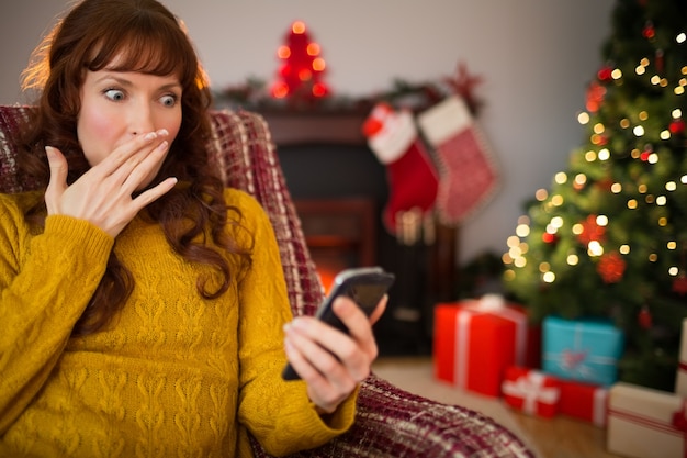 Redhead sorpreso guardando il suo cellulare a Natale