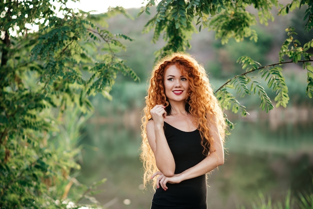 Redhead sorridente all&#39;aperto backlit dal sole, tiro di modo.