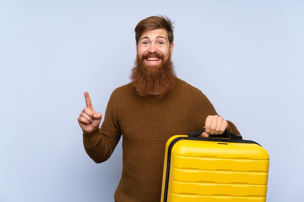 Redhead uomo con la barba lunga in possesso di una valigia rivolta verso l'alto una grande idea