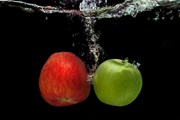 Ref e mela verde sono caduti in acqua con spruzzata isolata sul nero